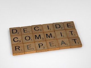 Scrabble tiles that say DECIDE, COMMIT, and REPEAT